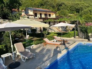 a swimming pool with two umbrellas and chairs next to a house at Vila Nikola in Bratesici