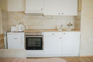 a kitchen with white cabinets and an oven at BelleVu studio apartman in Vukovar