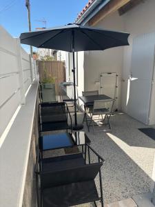 Un grupo de sillas y una sombrilla en un patio. en T2 neuf avec terrasse privative proche gare, en Rochefort