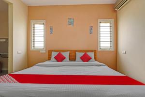 una camera da letto con un letto grande con cuscini rossi di Super Hotel O Indra Suites a Mysore