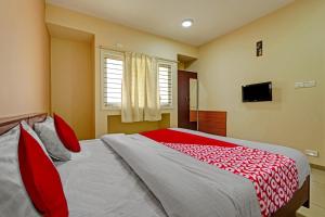 una camera da letto con un letto grande con cuscini rossi di Super Hotel O Indra Suites a Mysore Altre 20 foto