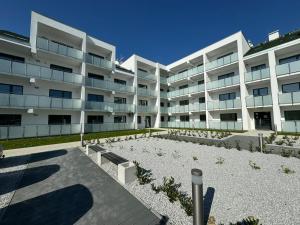 a large white building with a garden in front of it at Lulu Apartments - DEEP BLUE LAGOON apartament dwupokojowy - parking, Netflix - 350m od plaży! in Grzybowo