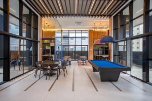 a pool table in a room with tables and chairs at Apto no All Batel finamente mobiliado perto do shopping Curitiba in Curitiba