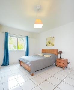 a bedroom with a bed and a window with blue curtains at Your west coast getaway in Flic-en-Flac +8 photos
