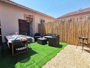 a patio with a table and chairs on grass at Le Cocon - Rénové I Clim I Terrasse I WIFI I Hypercentre in Miramas