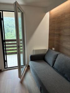 a living room with a couch and a large window at Soleneve in Passo del Tonale