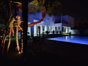 a building with a palm tree and a swimming pool at night at Luxury Villa with pool 6 min to Football Stadium CAF in Rabat