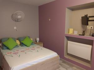 a bedroom with a bed with green pillows and a fan at fleurs de printemps - Jonquille chic in Vrécourt +25 photos
