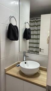 Un baño con un lavabo blanco y un espejo. en Depto Familiar Vista Mar 2D + Sofá Cama, en Antofagasta