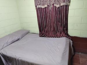 a bed in a room with a curtain on it at KameHouse Backpackers in San Salvador