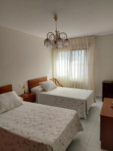 Un dormitorio con dos camas y una lámpara de araña. en Alojamiento Sena VUT LE-1254, en Villablino