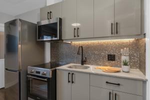 a kitchen with white cabinets and a stainless steel refrigerator at Adrian's Suites 2 Bedroom Family Suite in Wasaga Beach