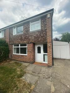 AylestoneにあるThe Stayover Spot Wigston Escapeの白い扉のあるレンガ造りの家