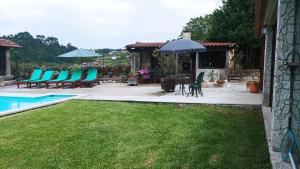 a patio with chairs and a table and an umbrella at Casa de Penim in Paredes de Coura