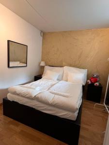 una camera da letto con un letto grande con lenzuola e cuscini bianchi di Appartment a Grorud