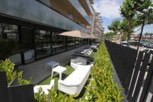 una fila de sillas blancas y una sombrilla frente a un edificio en Apartamentos Cambrils Playa Spa, en Cambrils