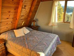 Un dormitorio con una cama en una cabaña de troncos en Cabaña Rodar 2, en Villa Pehuenia