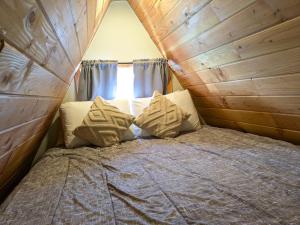 a bed in a room with a wooden wall at Mushroom Cabin on Homestead w Hot Tub in Brew Bay