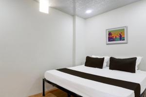 a bedroom with a white bed with black pillows at Hotel O Sky Villa in Nagpur