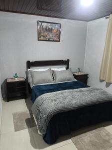 a bedroom with a bed with a blue comforter at Casa Florânia, Campos do Jordão in Campos do Jordão