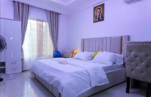 a white bedroom with a large bed and a window at Studio Apartment Ikeja GRA Lagos in Ikeja