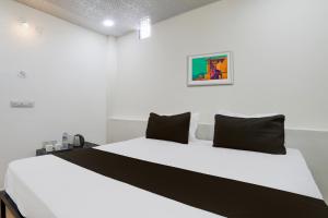 a bedroom with a white bed with black pillows at Hotel O Sky Villa in Nagpur +22 photos
