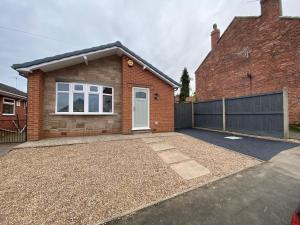 a brick house with a white door and a fence at Bungalow 2BR Parking Shower in Heanor