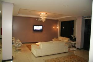 a living room with a couch and a tv on a wall at Thile Park Hotel in Jataí