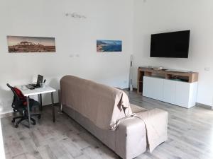 a living room with a couch and a desk and a television at Appartamento Montevago Centro in Montevago