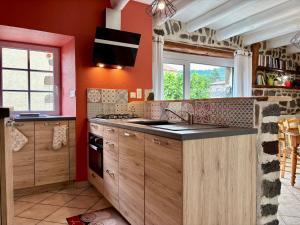 una cucina con pareti arancioni, lavandino e piano cottura di Gîte pittoresque en campagne près du Puy-en-Velay, idéal pour nature et St-Jacques de Compostelle - FR-1-582-451 a Séneujols Altre 11 foto