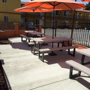 a group of picnic tables with orange umbrellas at Studio City Inn - Near Universal Studios Hollywood in Los Angeles
