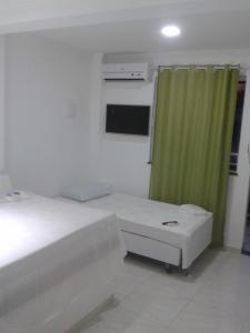 a bedroom with a bed and a green curtain at pousada do rei in Pedra de Guaratiba