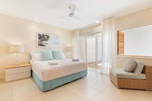 Un dormitorio con una cama y una silla y una ventana. en Mirage Resort Villa 128 with access to Sheraton Facilities, en Port Douglas