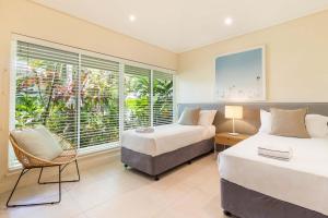 Un dormitorio con dos camas y una ventana. en Mirage Resort Villa 128 with access to Sheraton Facilities, en Port Douglas