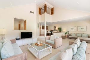 Una sala de estar con un sofá y un televisor. en Mirage Resort Villa 128 with access to Sheraton Facilities, en Port Douglas