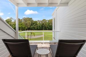 Un porche cubierto con dos sillas y vista a un campo de golf. en Mirage Resort Villa 134 with access to Sheraton Facilities, en Port Douglas