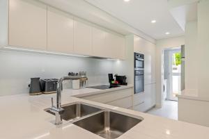 cocina con armarios blancos y fregadero de acero inoxidable en Mirage Resort Villa 134 with access to Sheraton Facilities, en Port Douglas