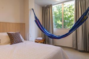 a bedroom with a bed and a hammock in front of a window at New Pueblito Suites - Cerca a la Playa in Cartagena de Indias