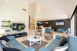 uma sala de estar com um sofá azul e uma TV em Mirage Resort Villa 140 with access to Sheraton Facilities em Port Douglas