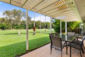 un patio con mesa, sillas y césped en Mirage Resort Villa 142 with access to Sheraton Facilities, en Port Douglas