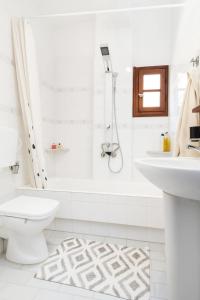 a white bathroom with a toilet and a sink at Rodi Apartment 2 in Kamari +14 photos