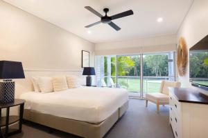Un dormitorio con una cama y un ventilador de techo. en Mirage Resort Villa 156 with access to Sheraton Facilities, en Port Douglas