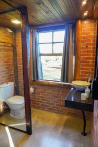 Un baño con inodoro, lavabo y ventana. en Chalé Celeiro em frente ao lago, en Rolante