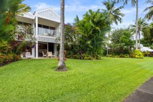 a house with a lawn and palm trees at Mirage Resort Villa 157 with access to Sheraton Facilities in Port Douglas