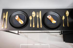 a shelf with black plates and gold forks and knives at Palermo Luxury Rooms White in Palermo