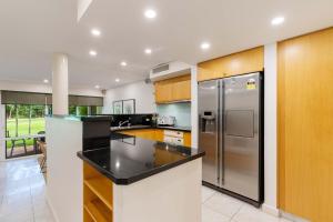 a kitchen with a stainless steel refrigerator and wooden cabinets at Mirage Resort Villa 158 with access to Sheraton Facilities in Port Douglas +1 photo