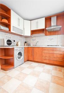 a kitchen with wooden cabinets and a washer and dryer at PARK! Nezavisimosti 78 in Minsk