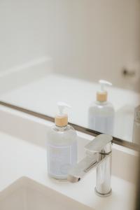 a bottle of soap sitting on a bathroom sink in front of a mirror at A Gentle Hideaway in the Urban Forest WEST END downtown Vancouver in Vancouver