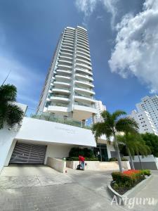 a tall white building with palm trees in front of it at Oceanfront Luxury - A pasos del Centro Histórico in Cartagena de Indias