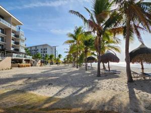 una spiaggia con palme e un edificio di Oceanfront, Caracol Beach a El Quindio